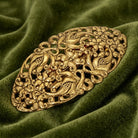 Decorative gold barrette on a green fabric background