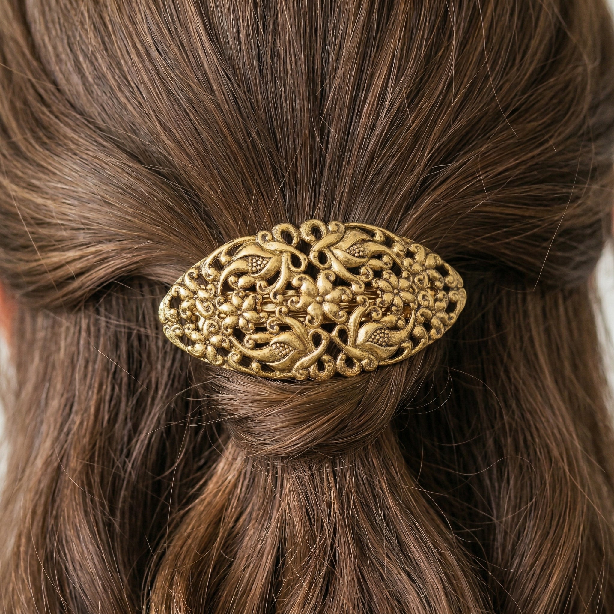 Gold hair barrette with intricate design on brown hair