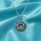 Silver necklace with a decorative iridescent wreath pendant spotted with AB crystals on a turquoise fabric background