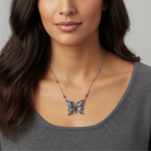 Woman wearing a butterfly pendant necklace against a neutral background