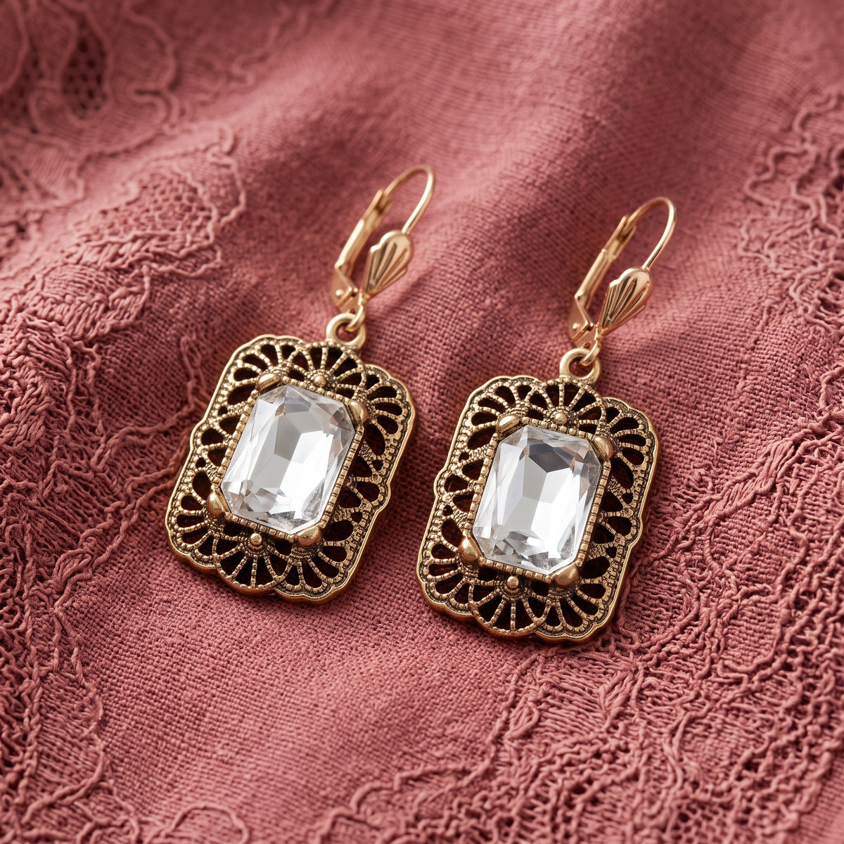 Brontë Filigree Octagon Clear Crystal Drop Earrings resting on coral pink laced fabric