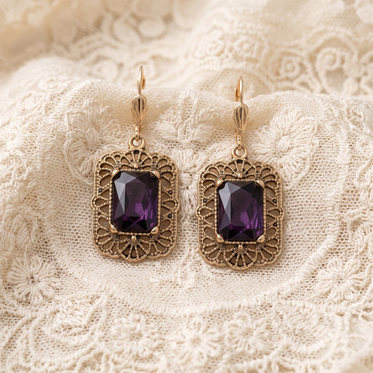 Brontë Filigree Octagon Amethyst Crystal Drop Earrings resting on white laced fabric
