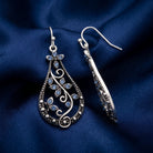 Teardrop Vine Light Sapphire Crystal Drop Earrings on a blue fabric background