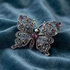 Antiqued Butterfly Multi Color Crystals Brooch on a blue fabric background
