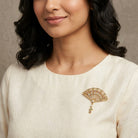 Woman wearing a Deco Blooming Elegance Multi Crystal & Faux Pearl Brooch on her beige outfit against a neutral background