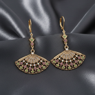Ornate gold earrings with crystals on a dark fabric background