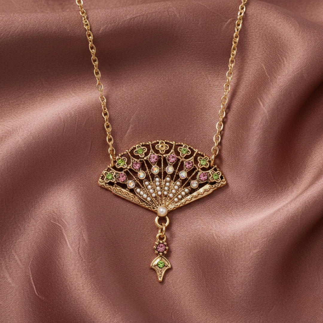 Gold necklace with a fan-shaped pendant on a muted pink satin background