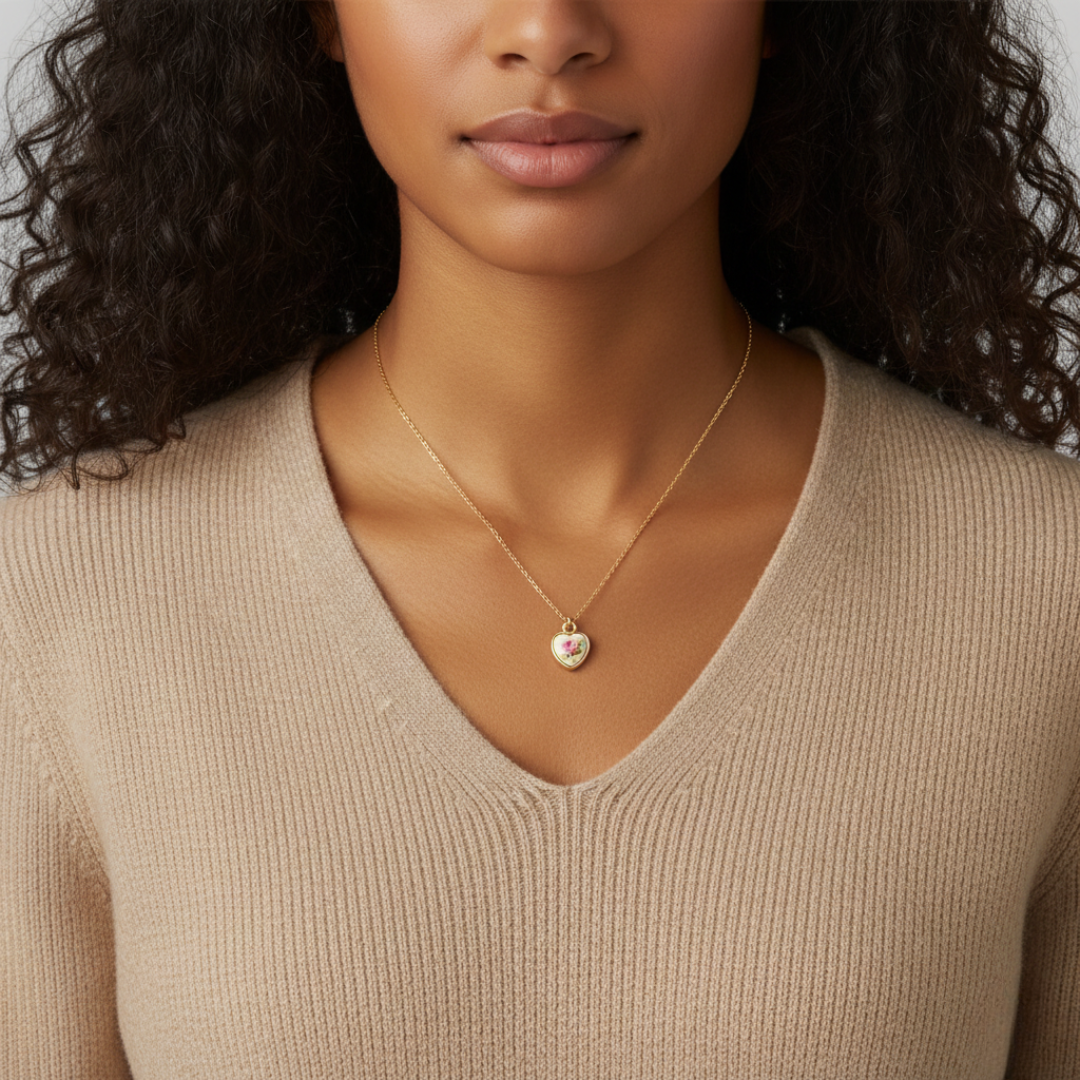 Woman wearing a gold necklace with a heart pendant against a neutral background