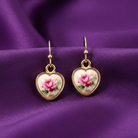 Heart-shaped earrings with floral design on a purple fabric background