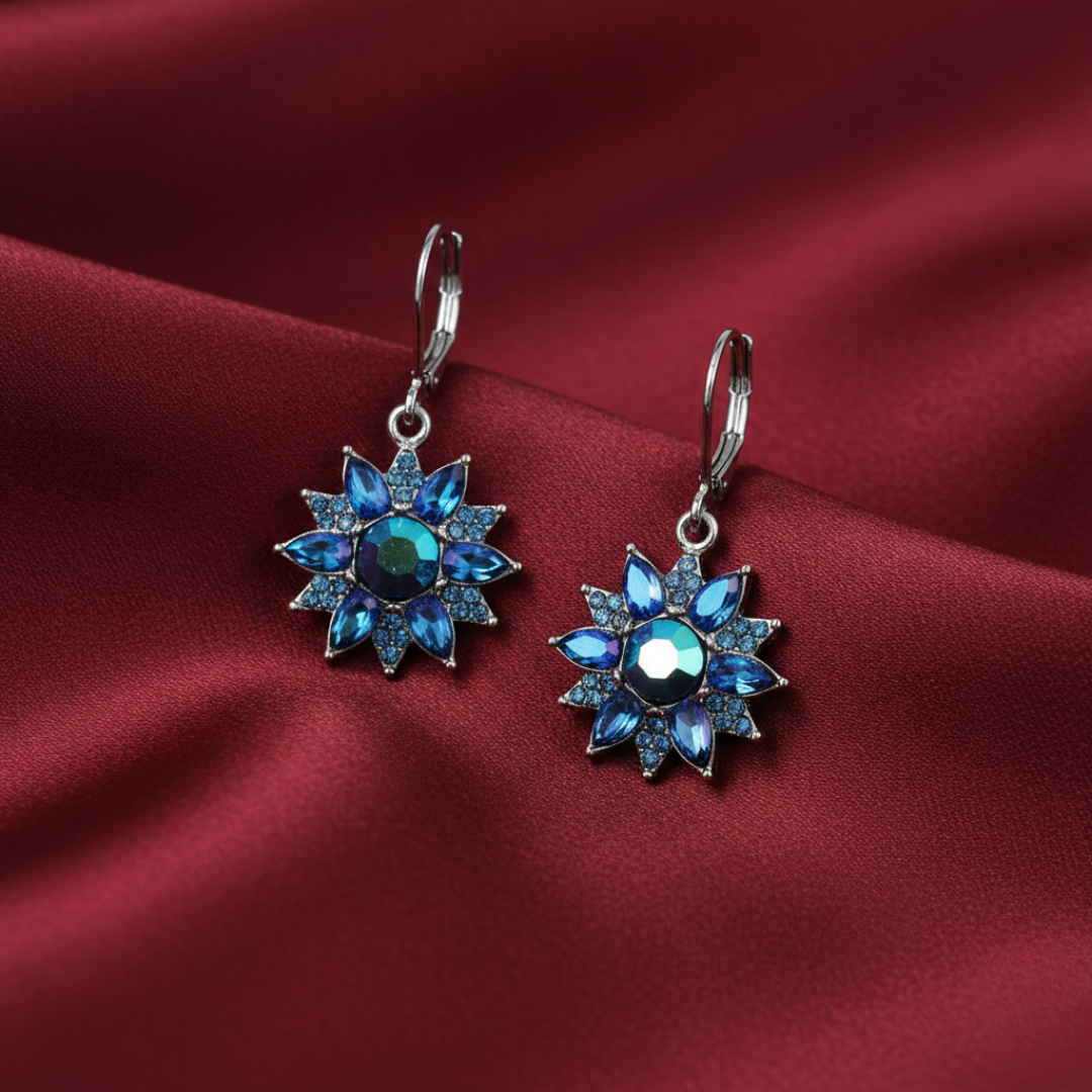 Regency Blue Iridescent Crystal Sunburst Drop Earrings on a red fabric background 