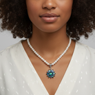 Woman wearing a pearl necklace with a shining blue floral pendant against a neutral background