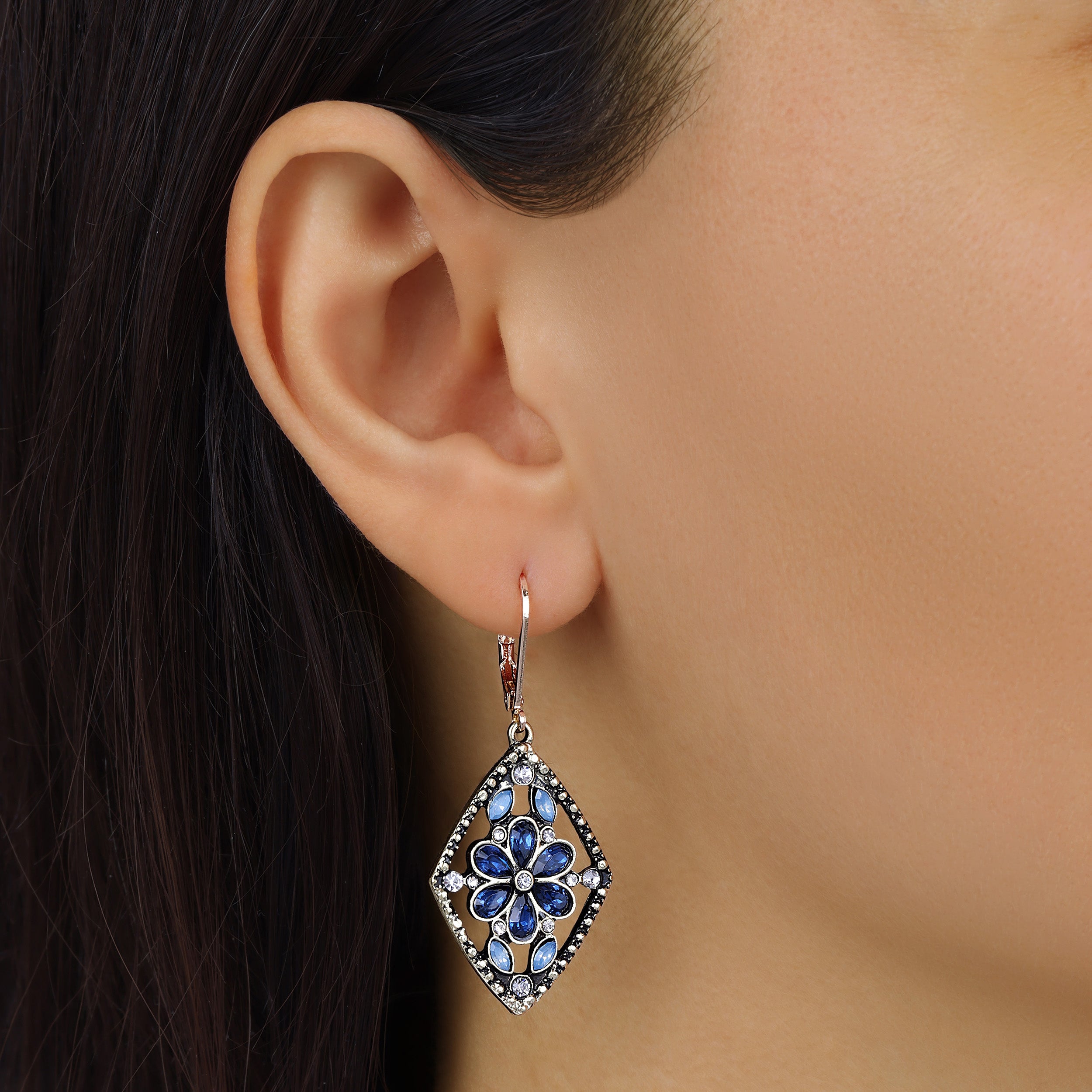 Close up of a woman wearing Diamond Shaped Flower Blue Crystal Drop Earrings