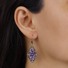 Close up of a woman wearing Diamond Shaped Flower Purple Crystal Drop Earrings