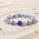 Beaded bracelet with blue and white pattern on a sandy background