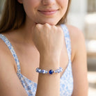 Woman wearing a blue beaded bracelet on her wrist with a blurred background