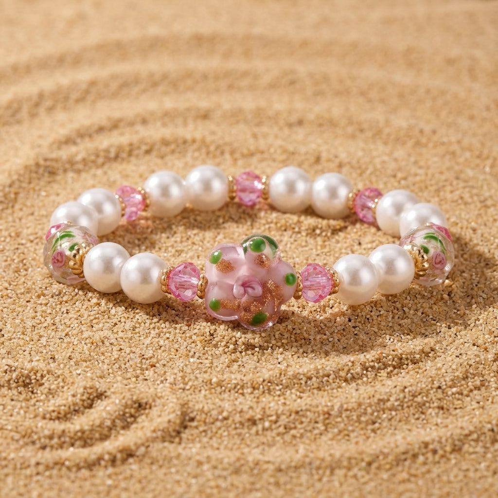 Blooming Flower & Round Faux Pearl Beaded Stretch Bracelet resting on sand