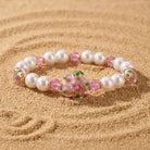 Blooming Flower & Round Faux Pearl Beaded Stretch Bracelet resting on sand