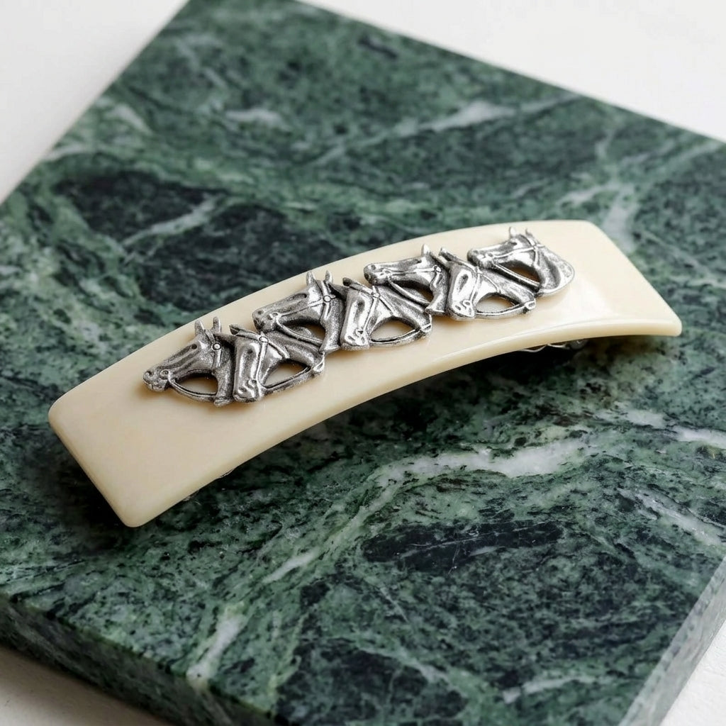 Ivory Racing Horses Hair Barrette on a green marble surface