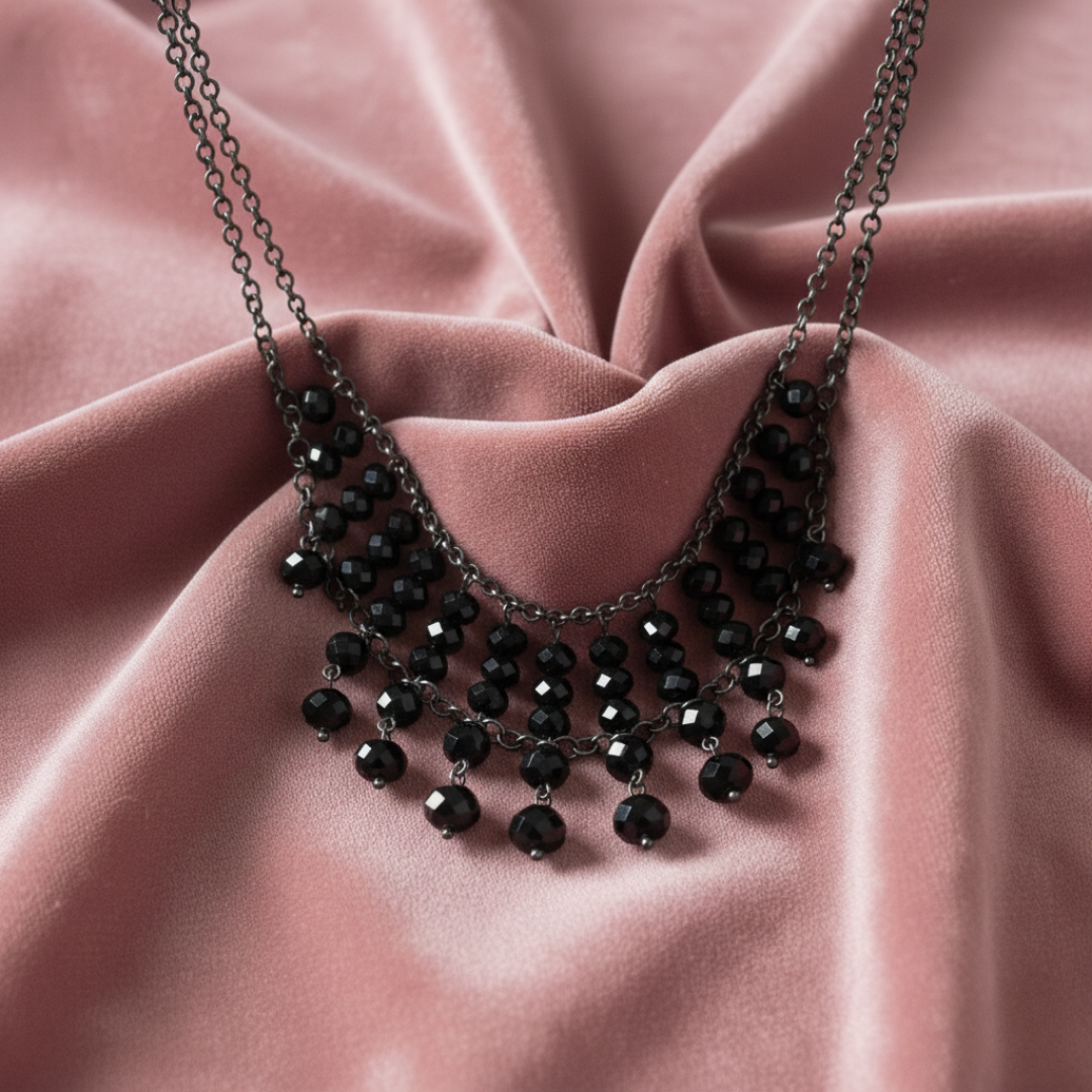 Black beaded necklace on a pink fabric background