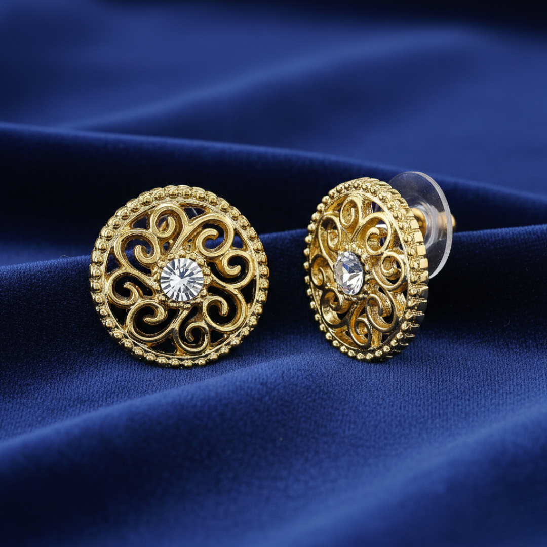 Gold earrings with intricate designs on a blue fabric background