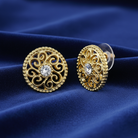 Gold earrings with intricate designs on a blue fabric background