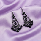 Black chandelier earrings on a purple satin background