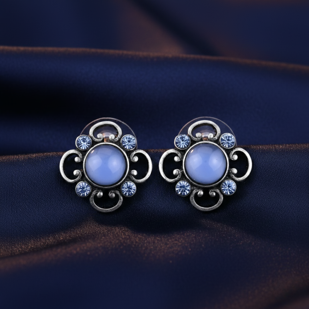 Pair of decorative earrings with blue gemstones on a dark fabric background