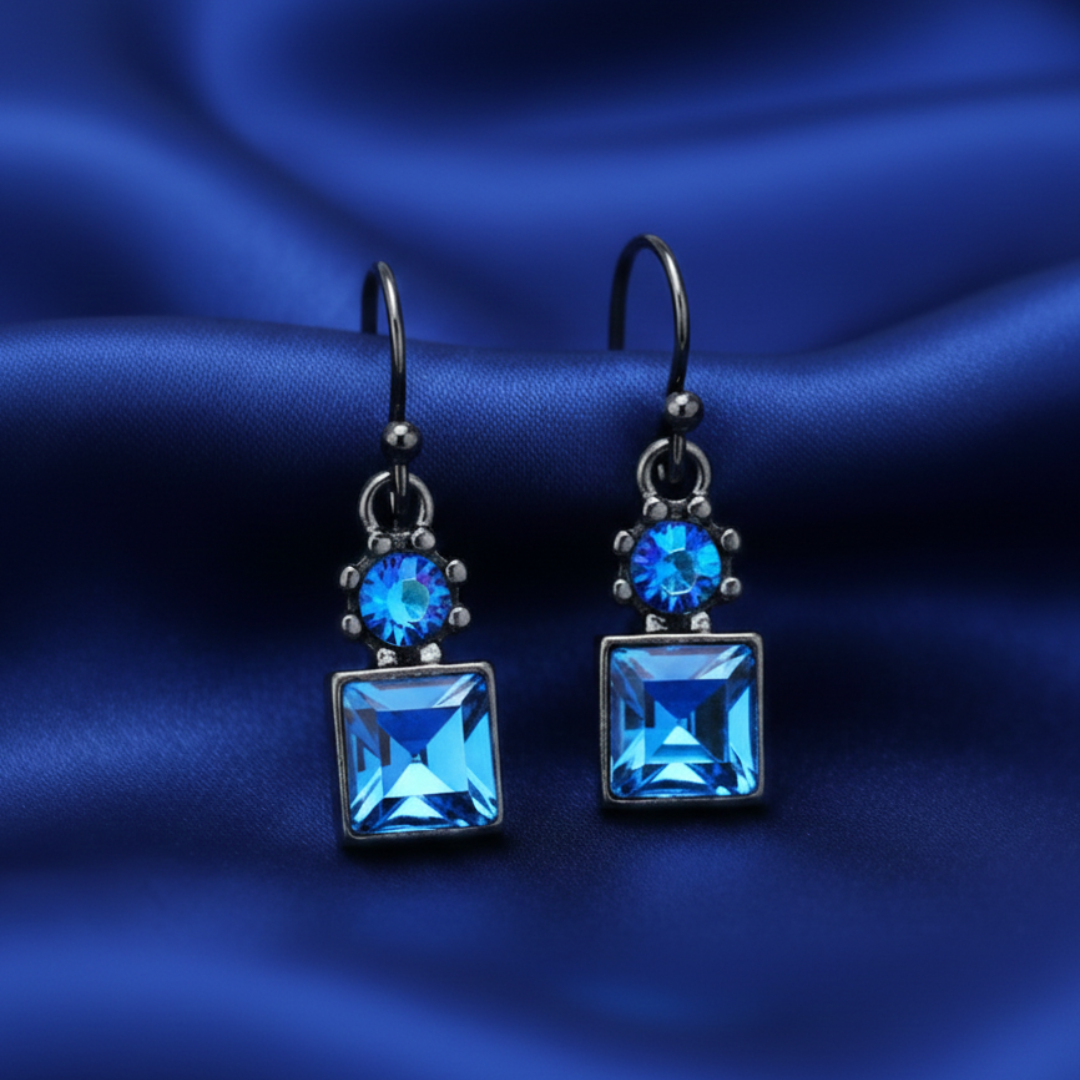 Pair of blue gemstone earrings on a blue satin background