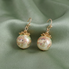 Pair of floral earrings on a green fabric background
