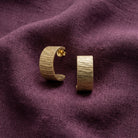 Gold Brushed Finish Half-Hoop Earrings deep purple fabric background.