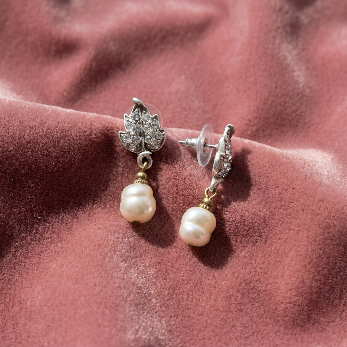 Antiquities Couture Crystal Baroque Faux Pearl Drop Post Earrings resting on pink fabric