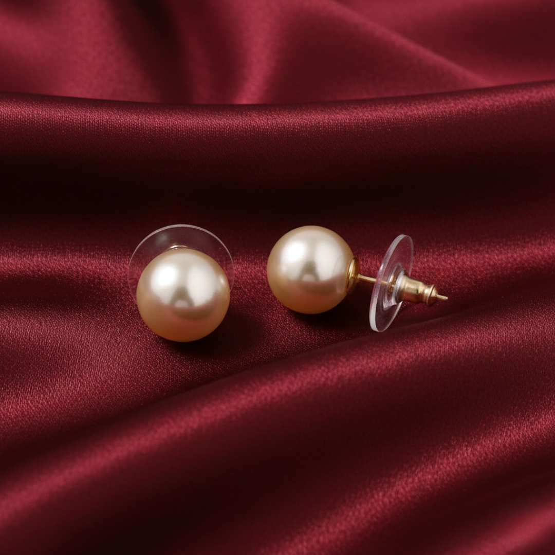 Ivory faux pearl earrings on a red satin background. 