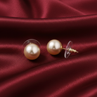 Ivory faux pearl earrings on a red satin background. 
