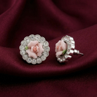 Pair of earrings with pink porcelain ose design on a red fabric background