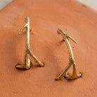Small Tree Branch Hoop Earrings displayed on a textured terracotta surface.