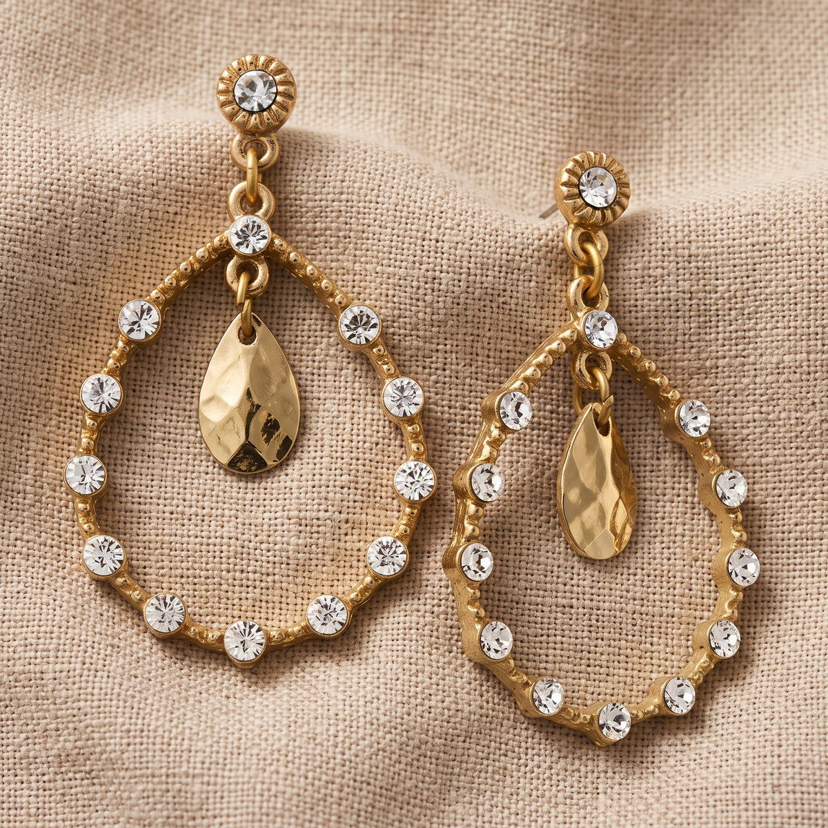 Golden Glitz Crystal Faceted Teardrop Earrings resting on beige fabric