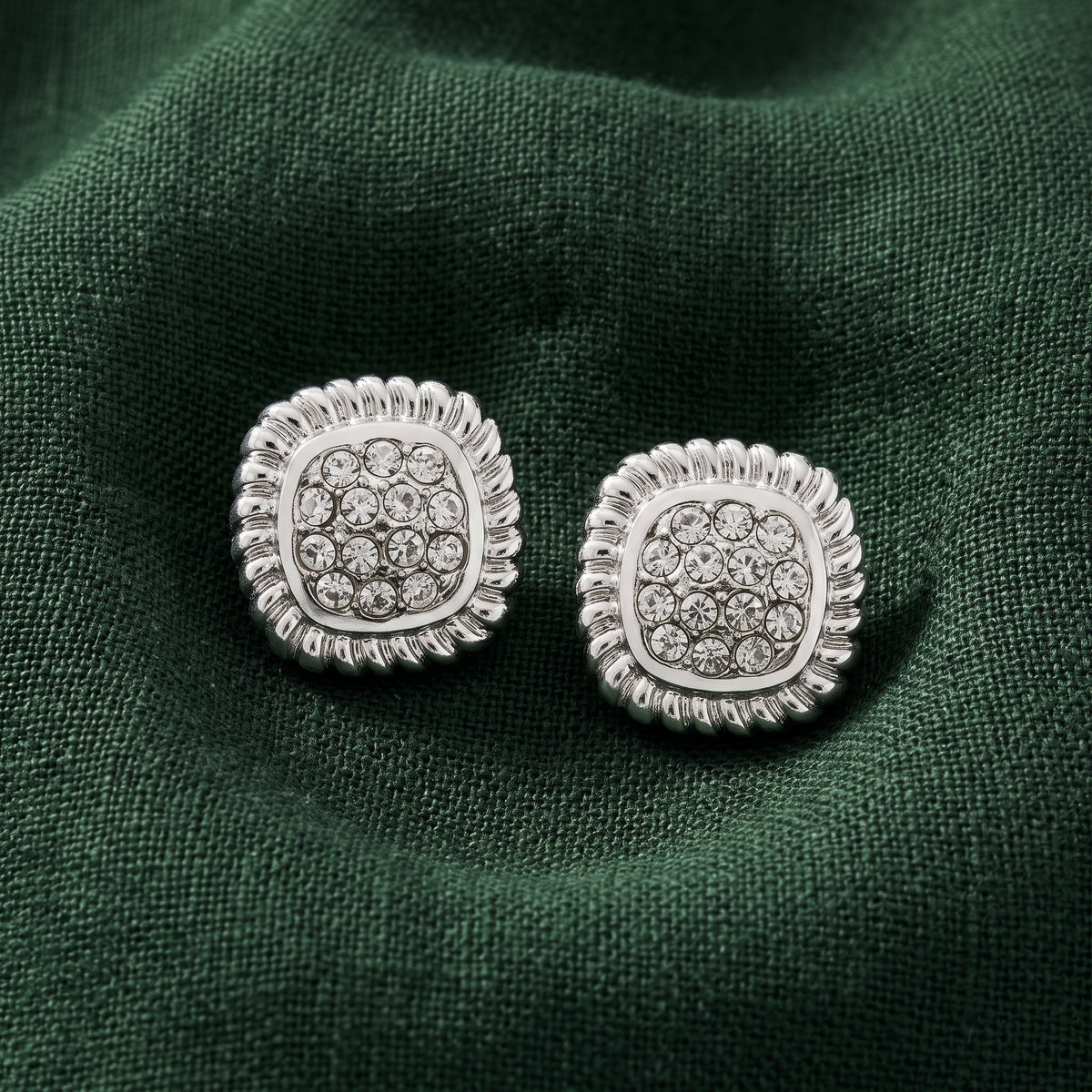 Square Pave Crystal Button Earrings resting on dark green linen