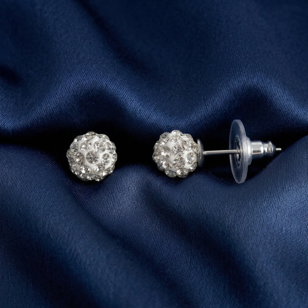 Silver stud earrings with clear crystals on a navy blue fabric background