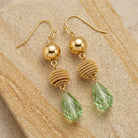 Light Peridot Green Beaded Teardrop Dangle Earrings resting on beige sandstone