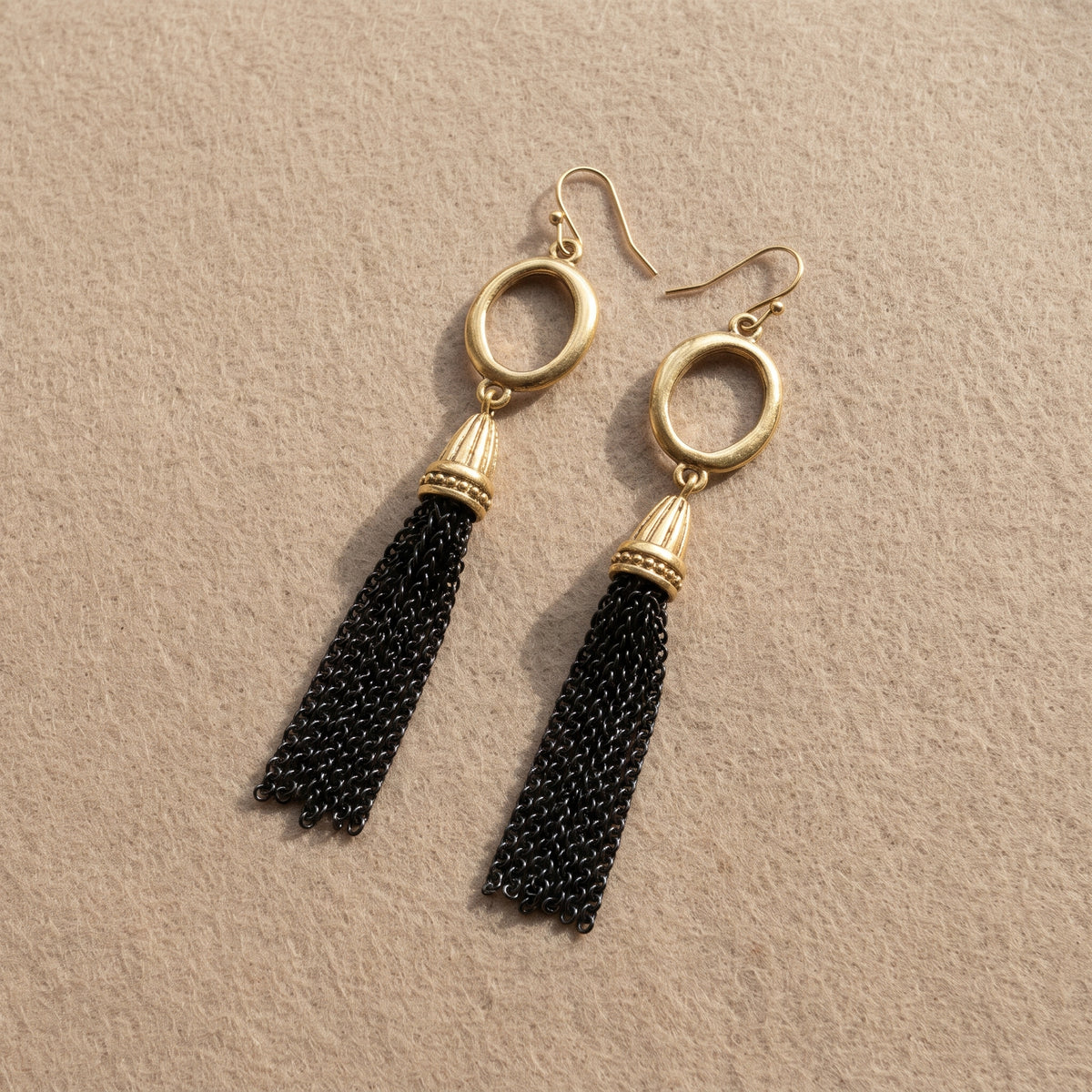 Antiquities Couture Two Tone Tassel Drop Earrings displayed on a textured beige surface.