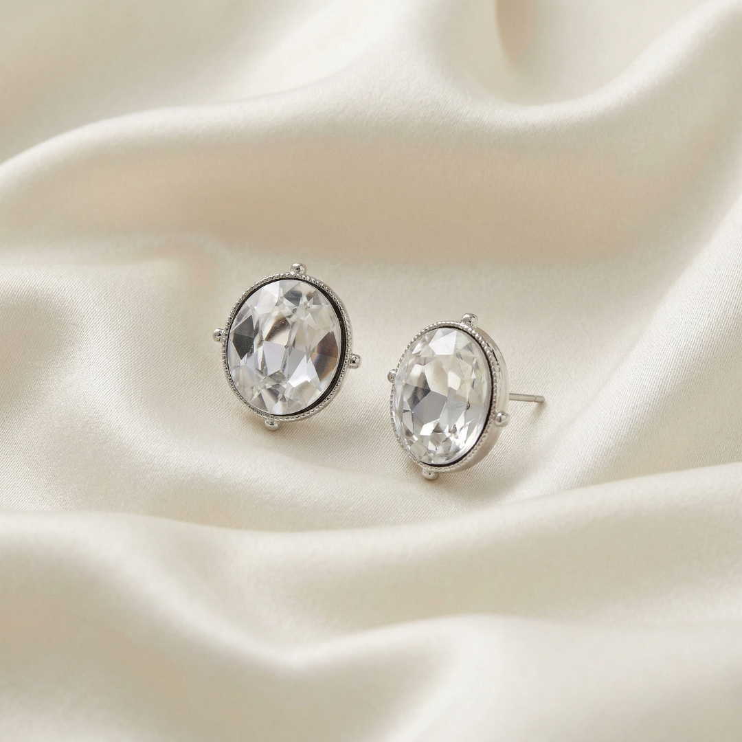 Pair of silver clear crystal earrings won a white fabric background