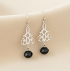 Silver earrings with black beads on a beige background