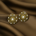 Gold floral earrings with clear stones on a brown fabric background.
