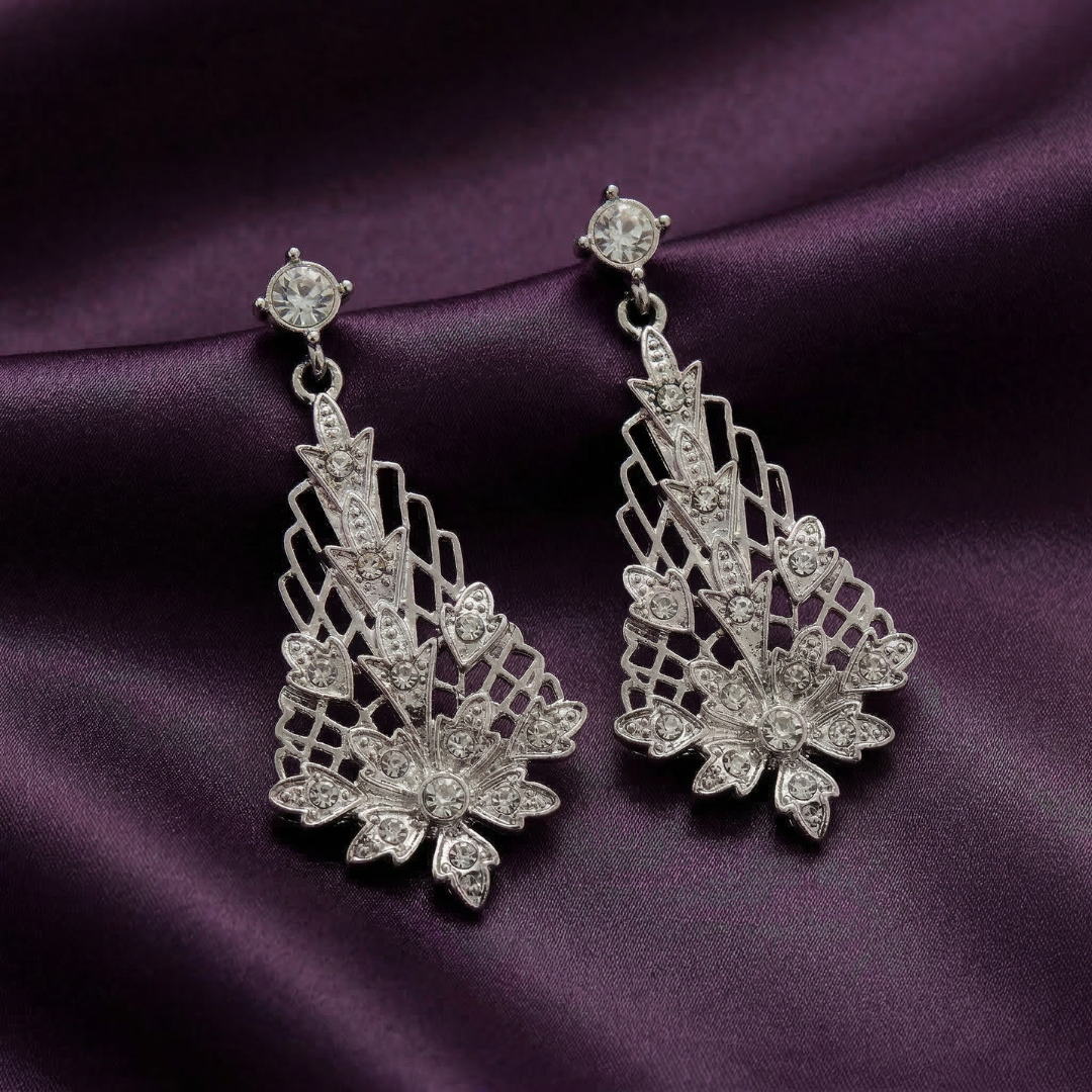 Pair of silver lantern-shaped floral earrings on a purple fabric background