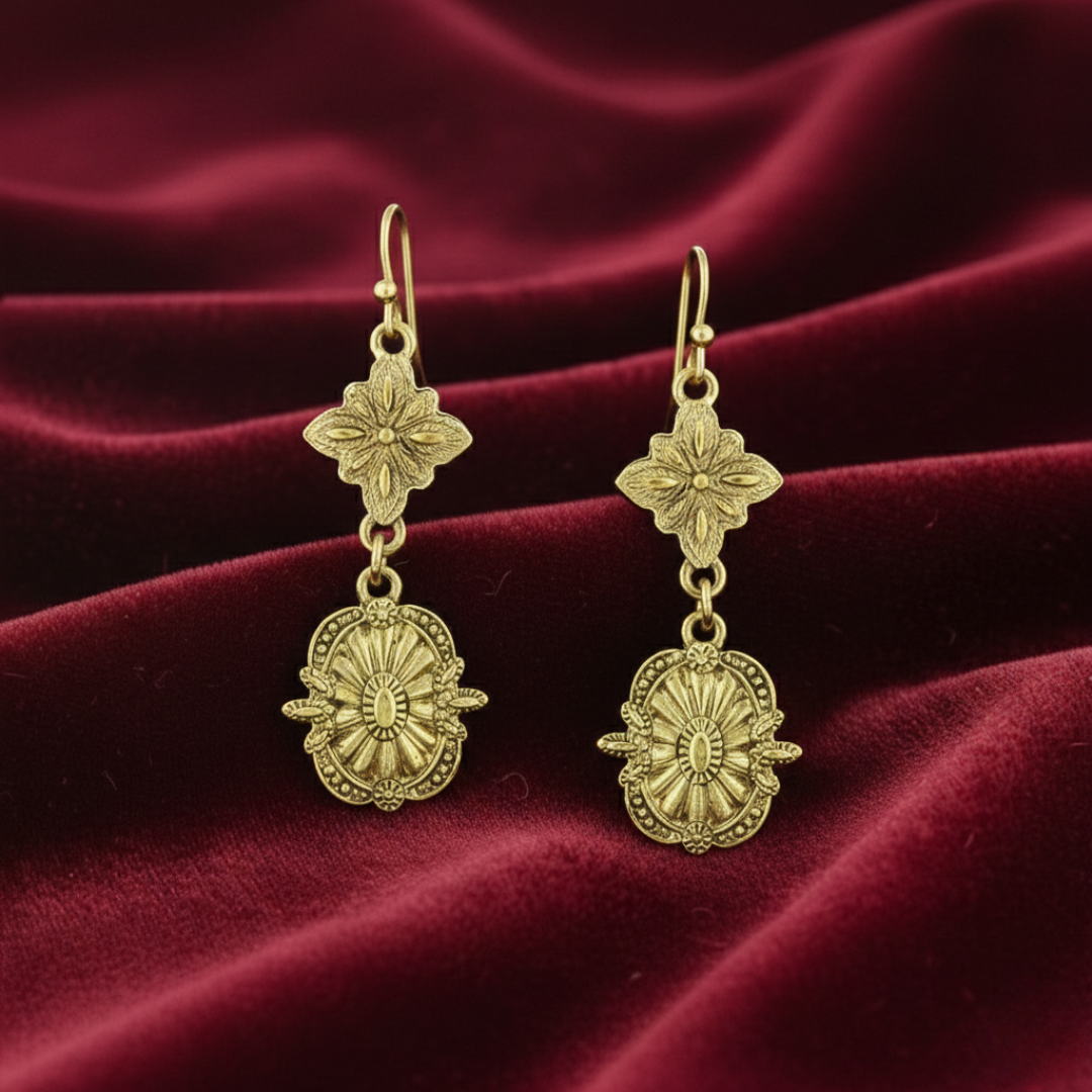 Gold earrings with floral designs on a red velvet background.