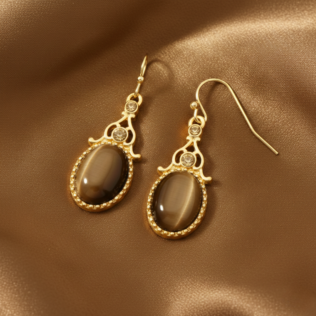 Gold earrings with brown stones on a brown fabric background