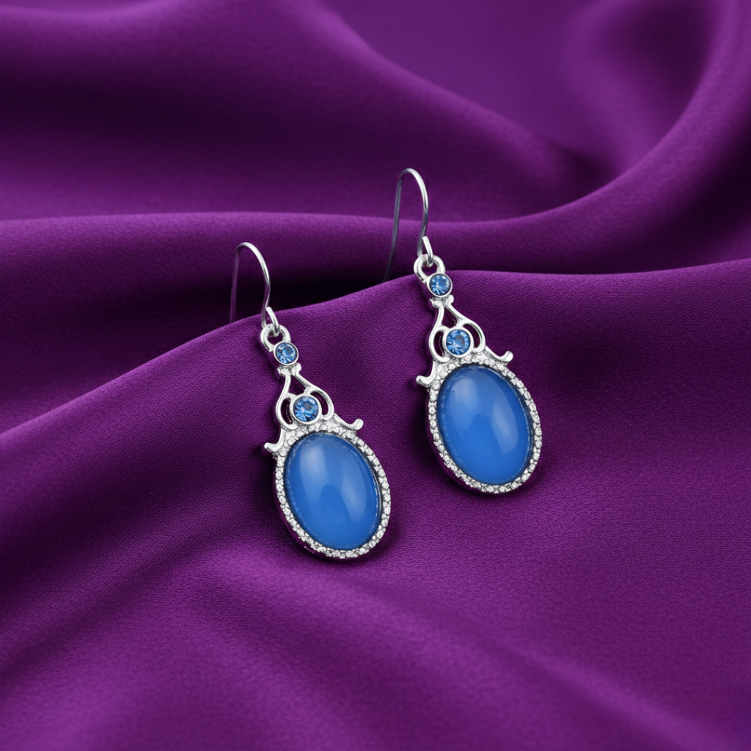Blue earrings with silver accents on a purple fabric background