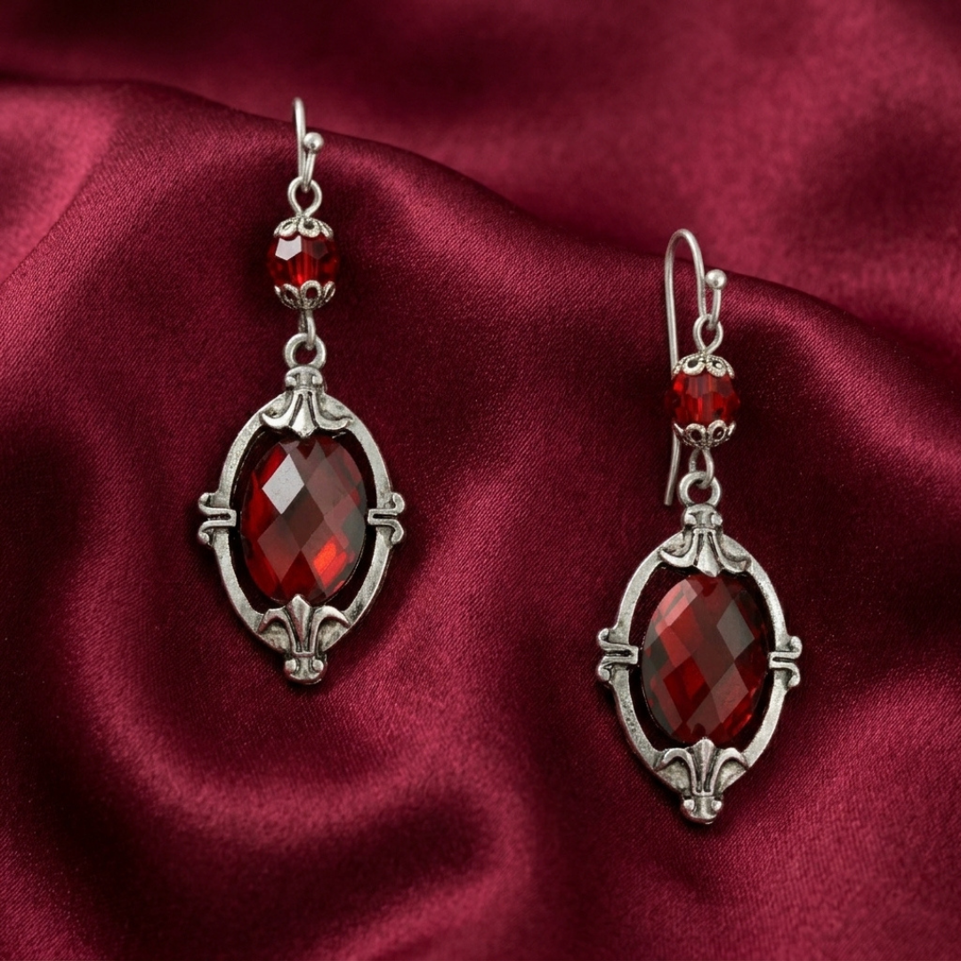 Pair of red crystal earrings on a red fabric background