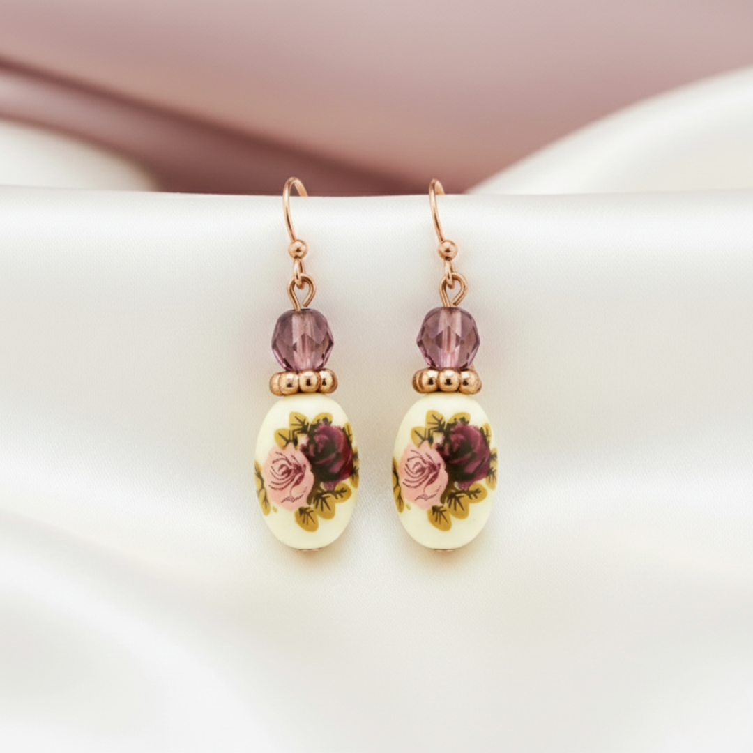 Pair of earrings with floral designs and an amethyst-tone accent. 