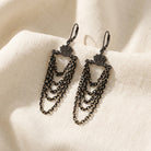 Eclipse Black And Gold Chain Layered Dangle Earrings resting on cream colored linen